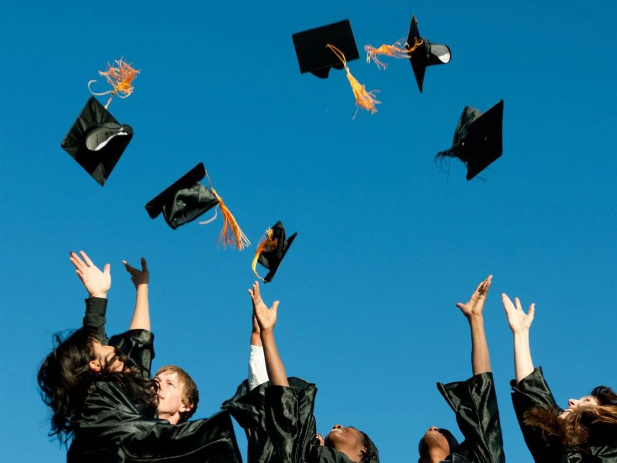 Graduates throwing their caps into a bright blue sky.